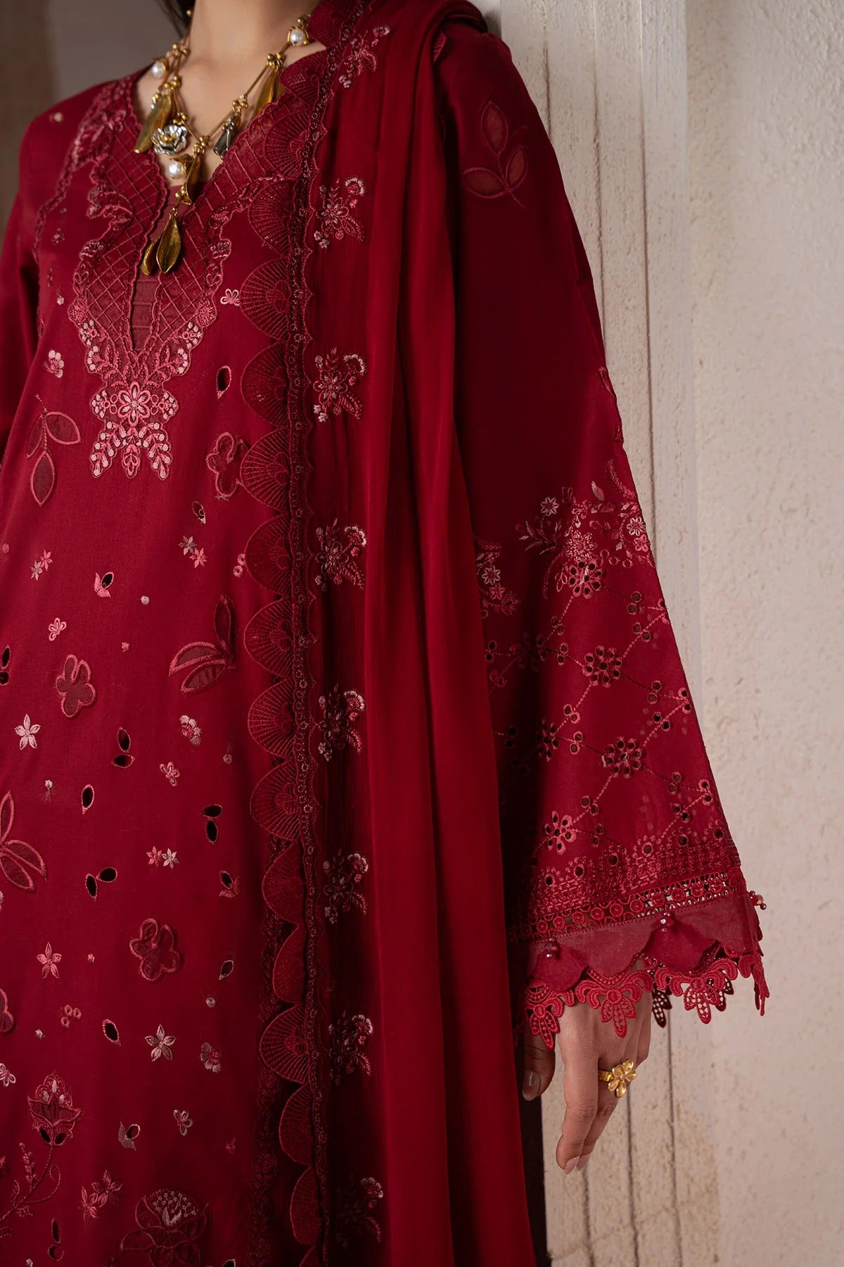 Red embroidered traditional outfit with intricate patterns on a neutral background