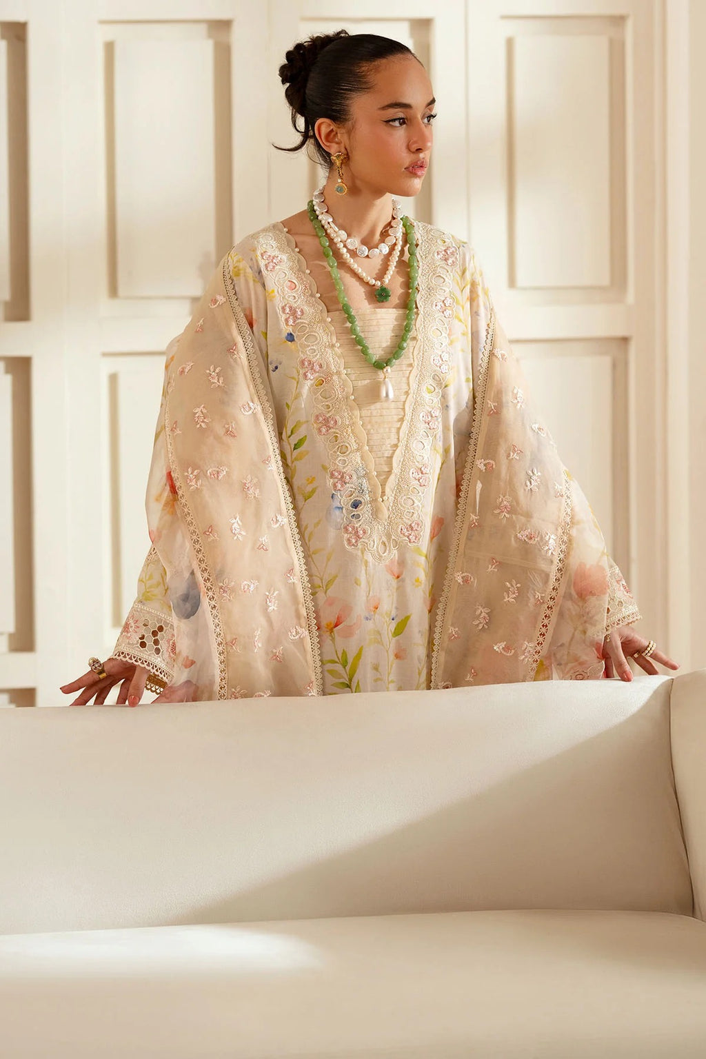 Woman wearing a floral embroidered outfit in a softly lit room.