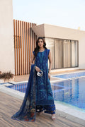 Woman in a blue traditional outfit standing by a poolside.