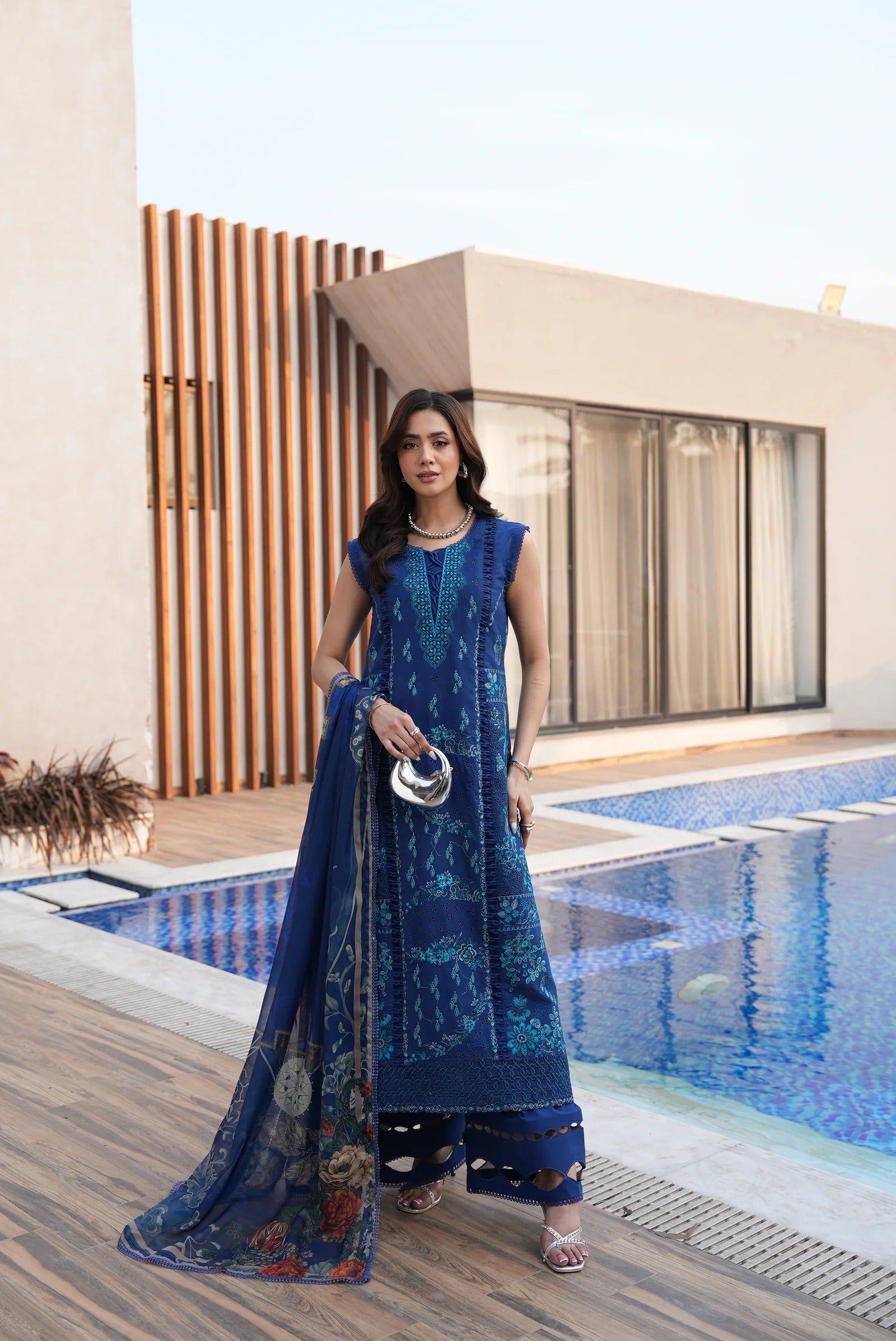 Woman in a blue traditional outfit standing by a poolside.