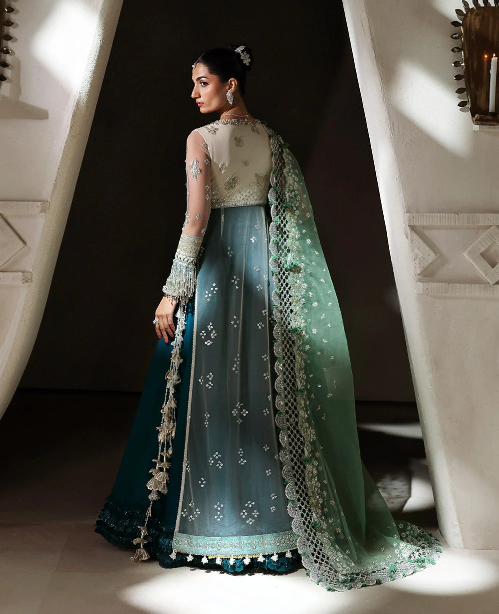Woman in a traditional outfit with intricate designs standing in a dimly lit room.