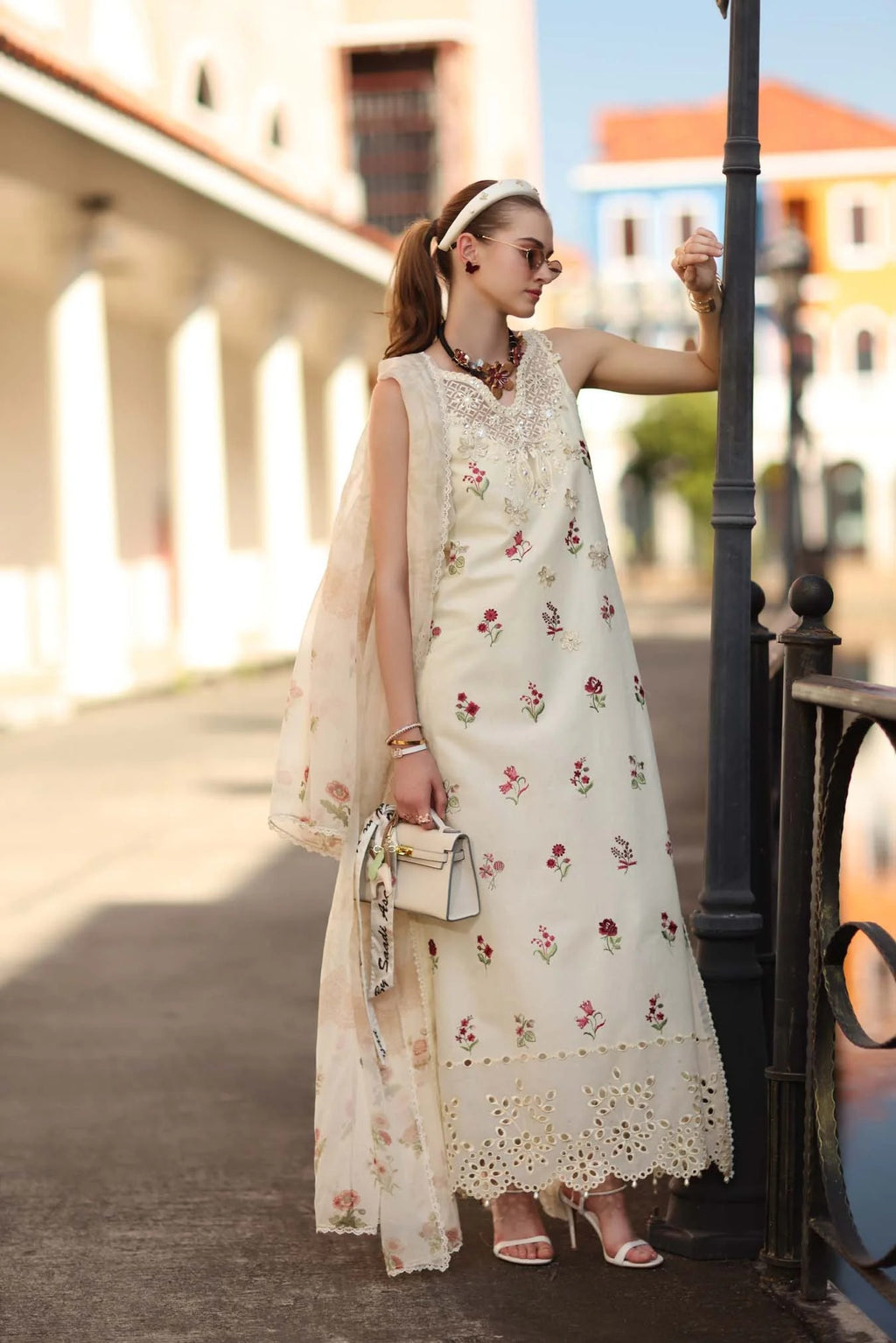 Woman in a floral dress standing on a street with buildings in the background