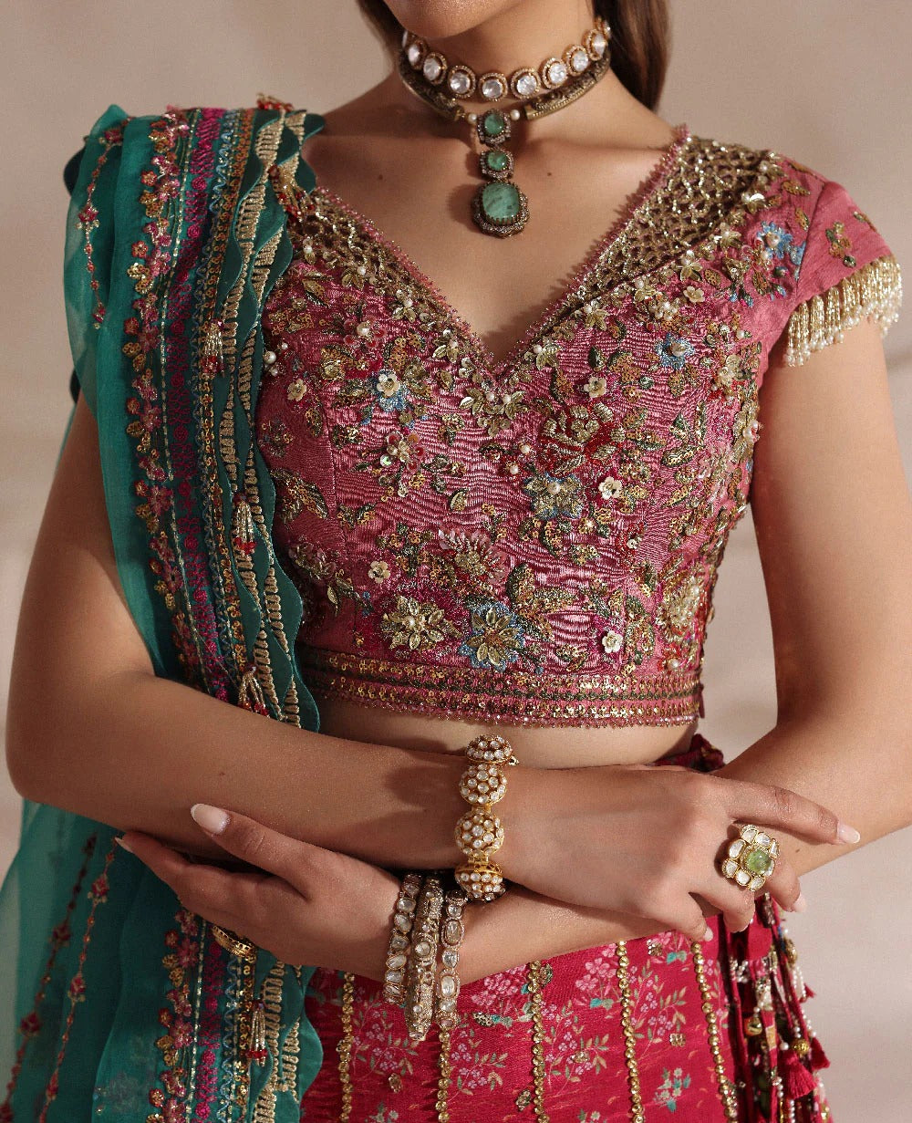 Woman wearing a pink embroidered blouse with gold detailing and a green dupatta.
