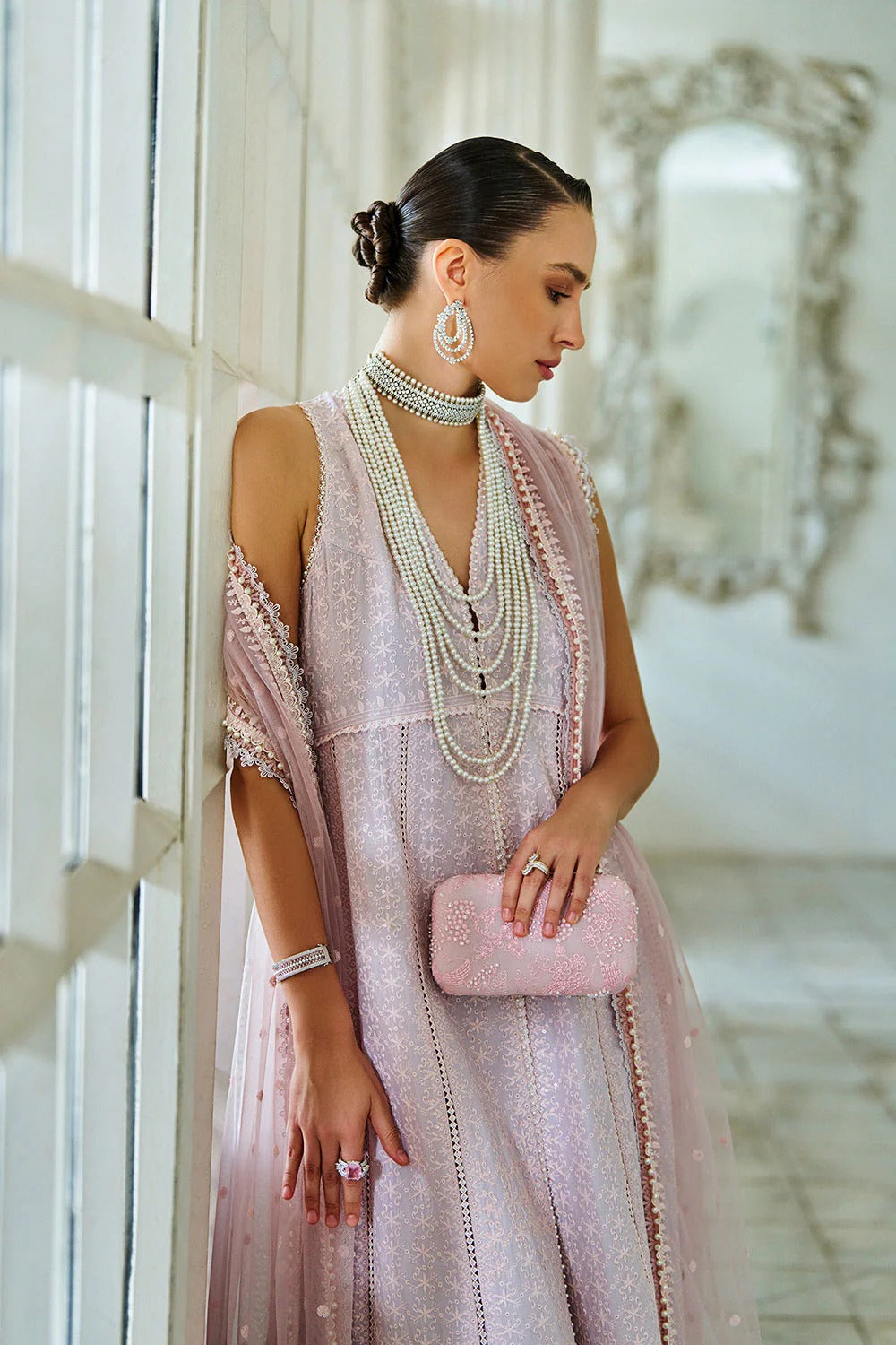 Woman in a pink dress with jewelry and a clutch in an elegant interior setting