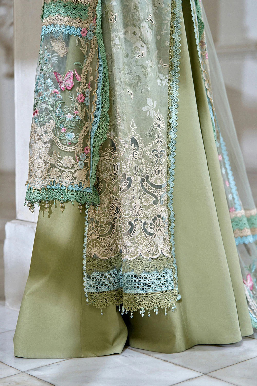 Traditional embroidered green outfit with floral patterns on a neutral background