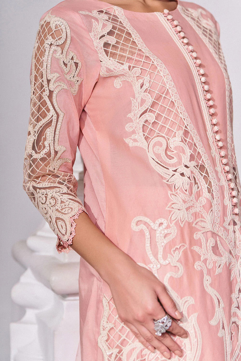 Pink lace dress with intricate detailing on a white background