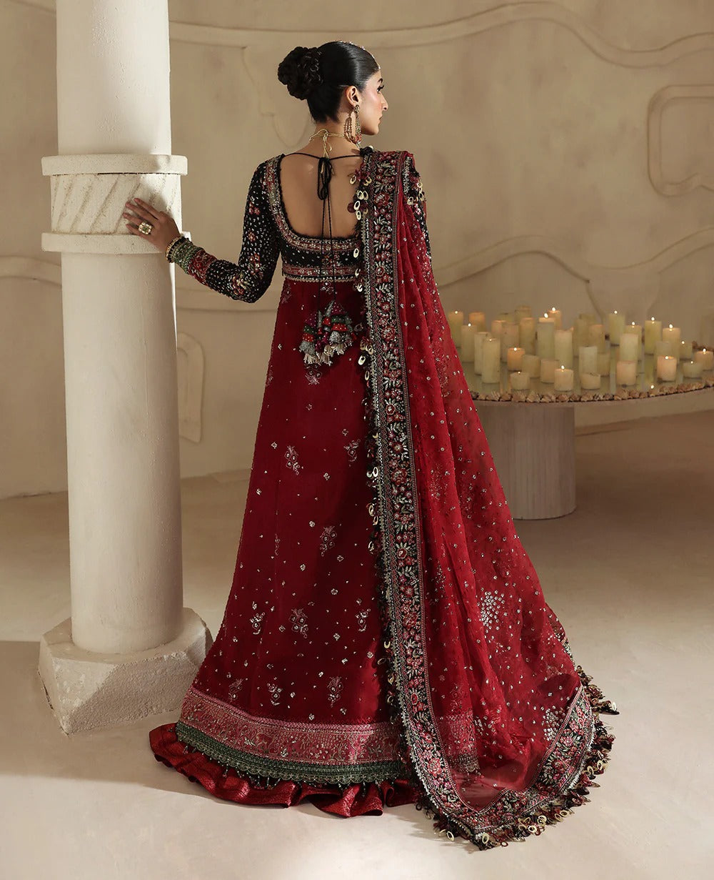 Woman in a red and black traditional outfit standing in a decorated room with candles.