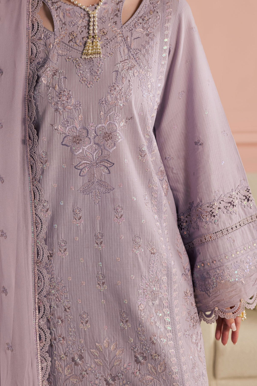 Lavender embroidered dress with intricate patterns on a beige background