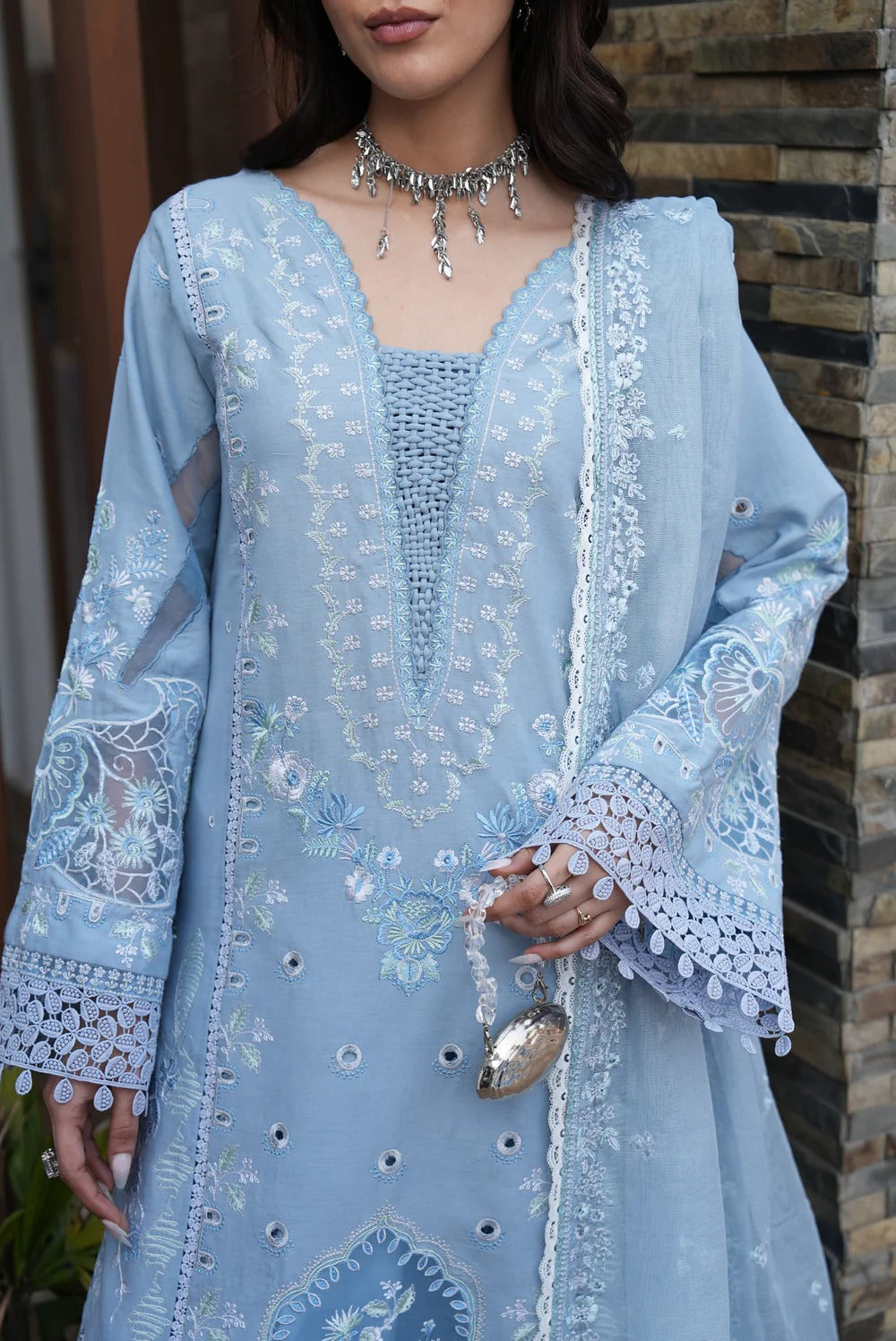 Light blue embroidered dress with matching jacket against a stone wall background