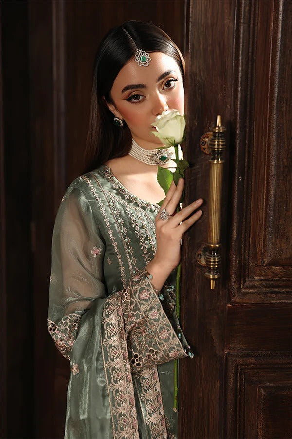 Woman in traditional attire holding a white rose in front of a wooden door.