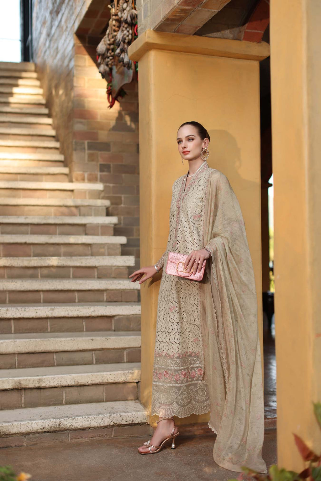 Woman in a traditional outfit standing on a staircase with a yellow wall.