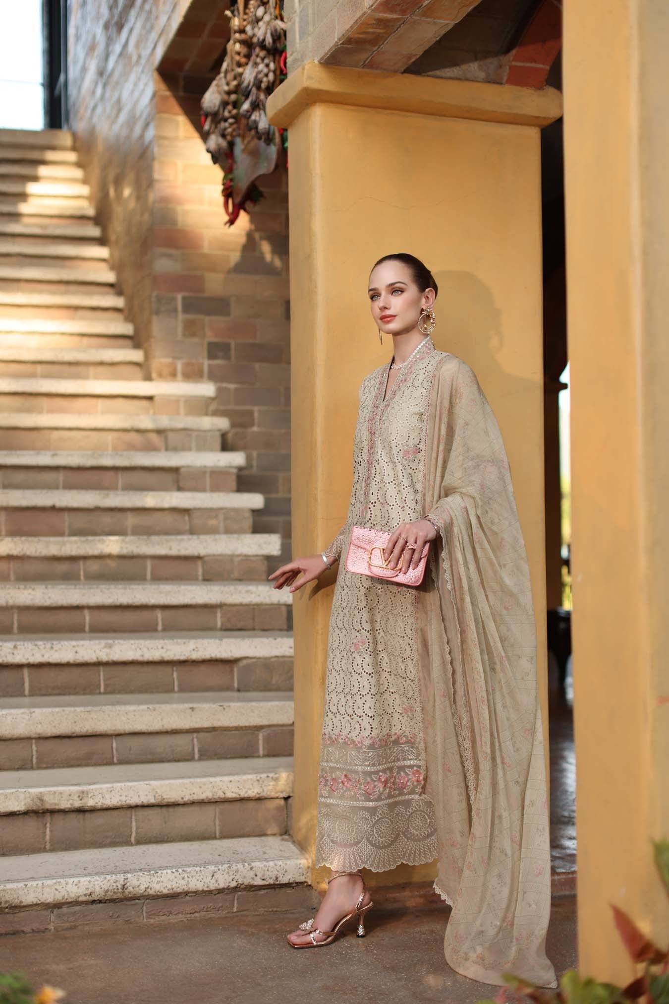 Woman in a traditional outfit standing on a staircase with a yellow wall.