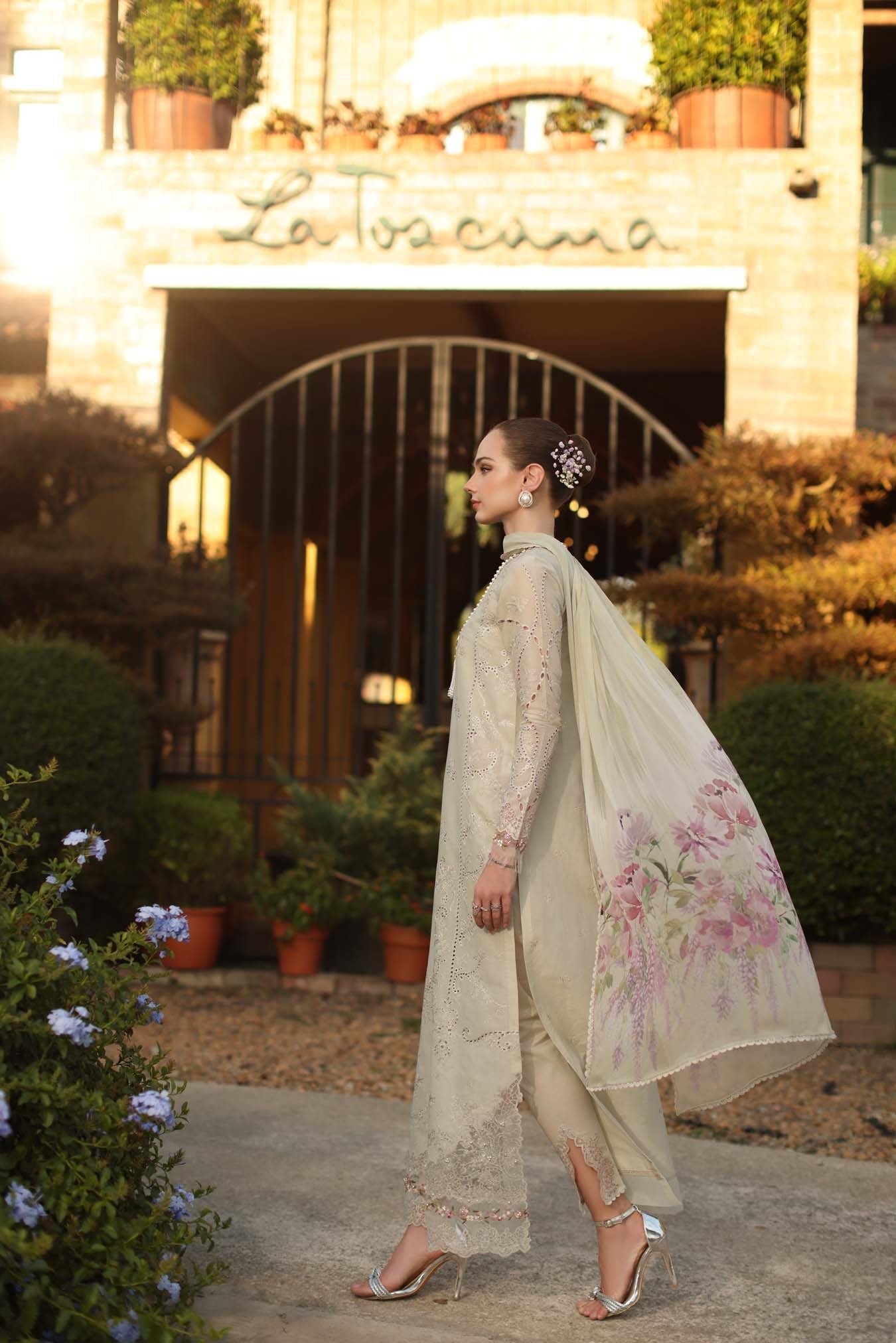 Woman in a traditional outfit standing in front of a building entrance.