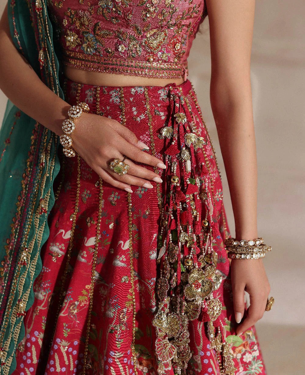 Red embroidered traditional outfit with gold details, green dupatta, and jewelry.