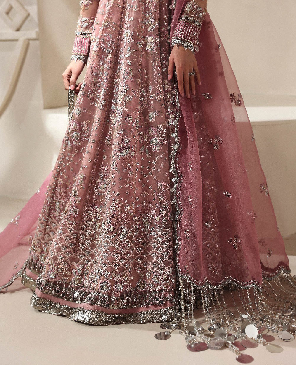 Pink embroidered traditional outfit with intricate designs on a neutral background