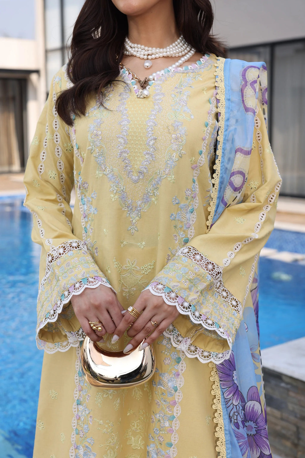 Woman in a yellow embroidered outfit by a poolside