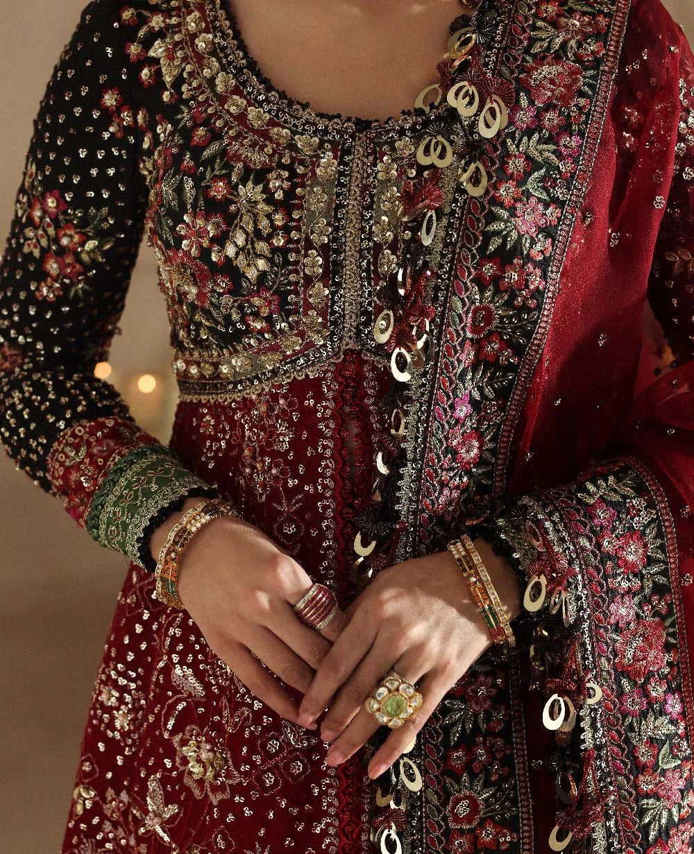 Close-up of a person wearing a intricately designed embroidered outfit with jewelry.