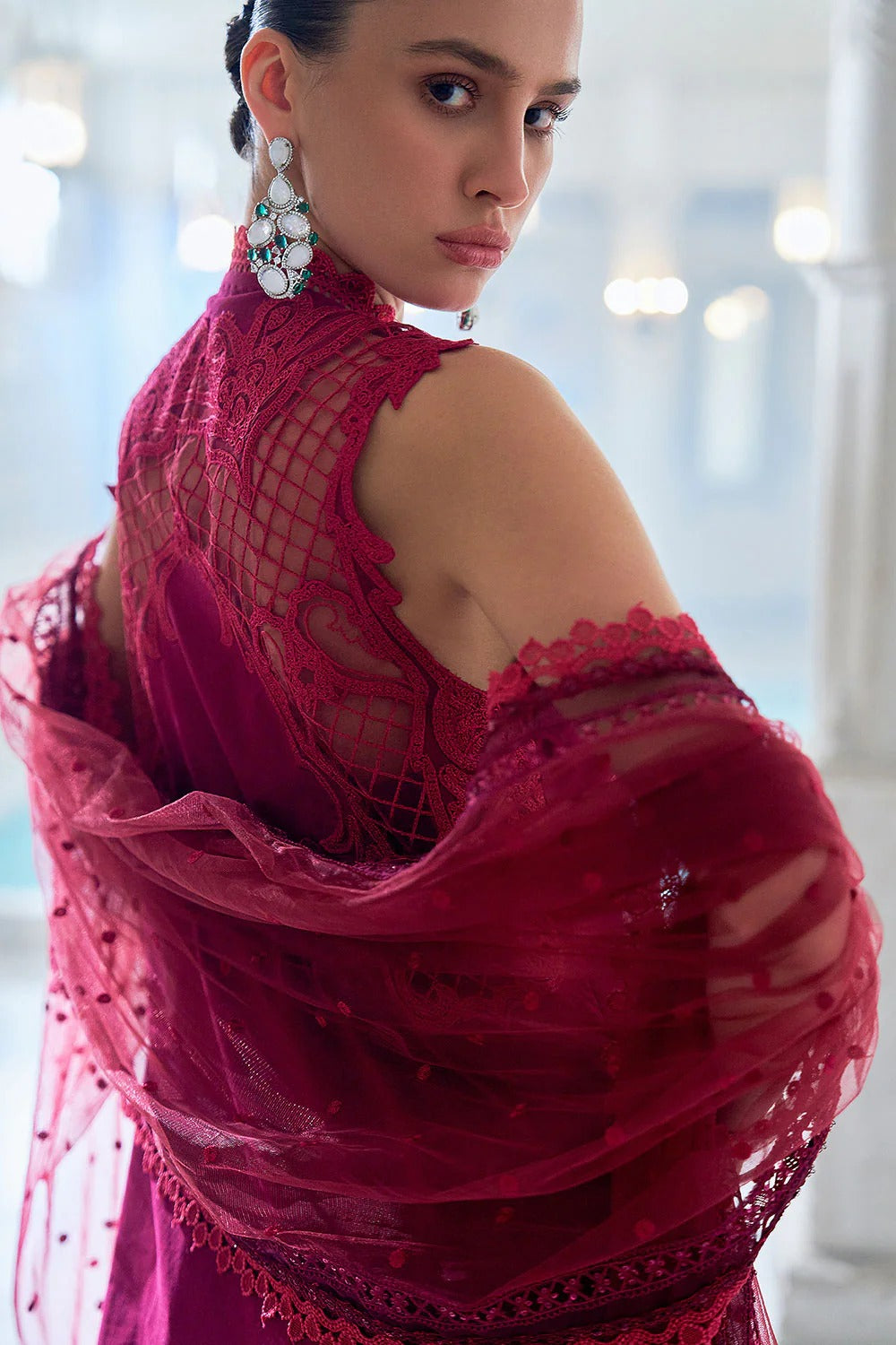 Woman wearing a red lace dress with a blurred indoor background