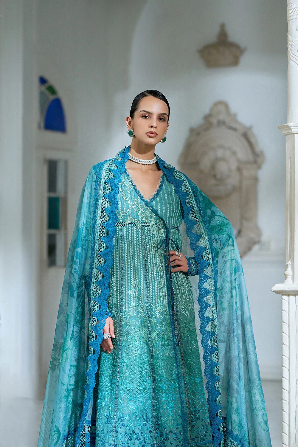 Woman wearing a turquoise embroidered outfit in an elegant interior setting