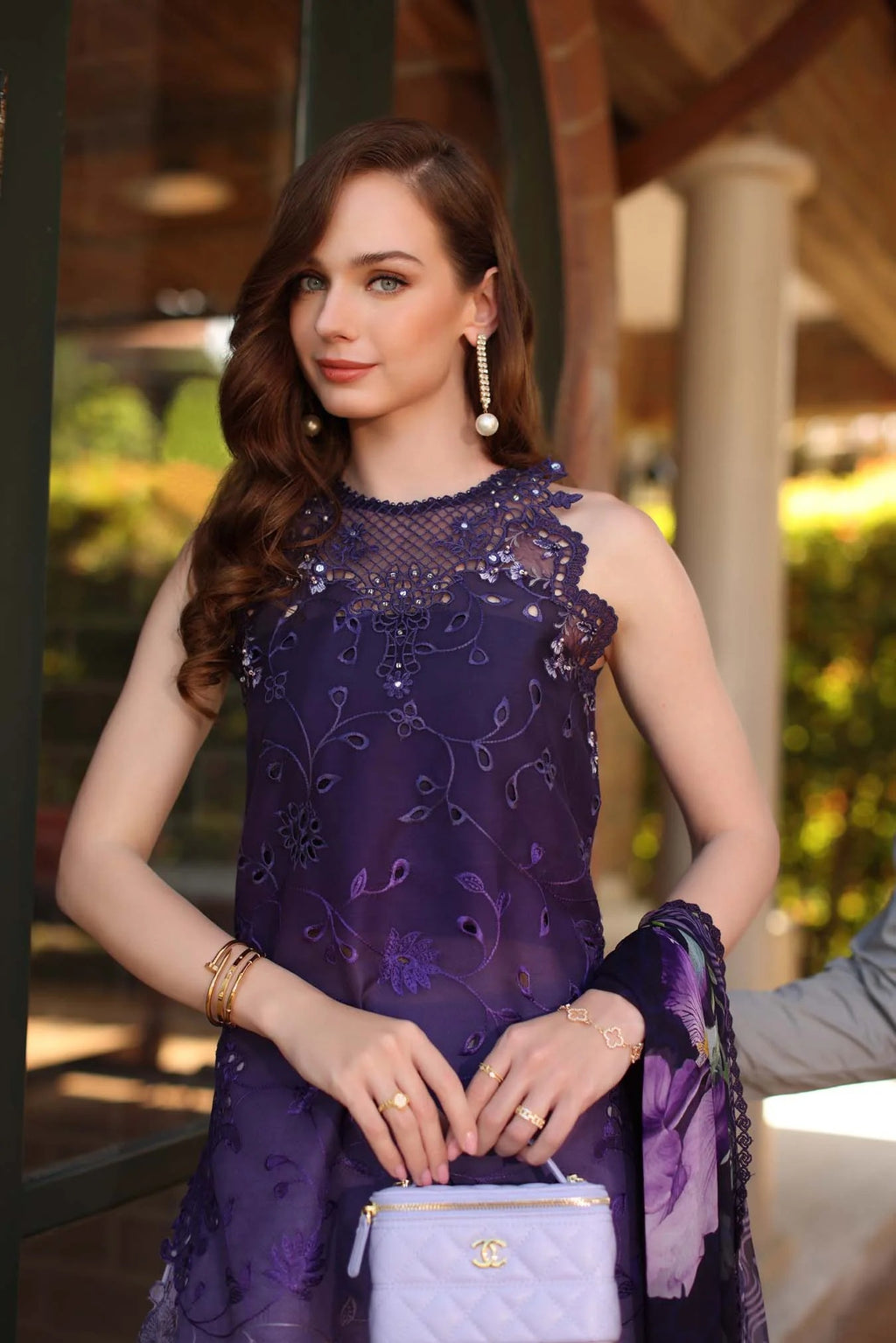 Woman in a purple dress holding a blue handbag outdoors