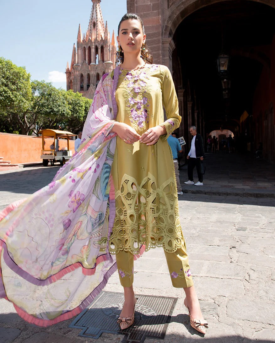 Woman in a yellow embroidered outfit with a colorful scarf in an outdoor setting.
