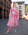 Woman in a pink traditional outfit with floral patterns standing on a street.