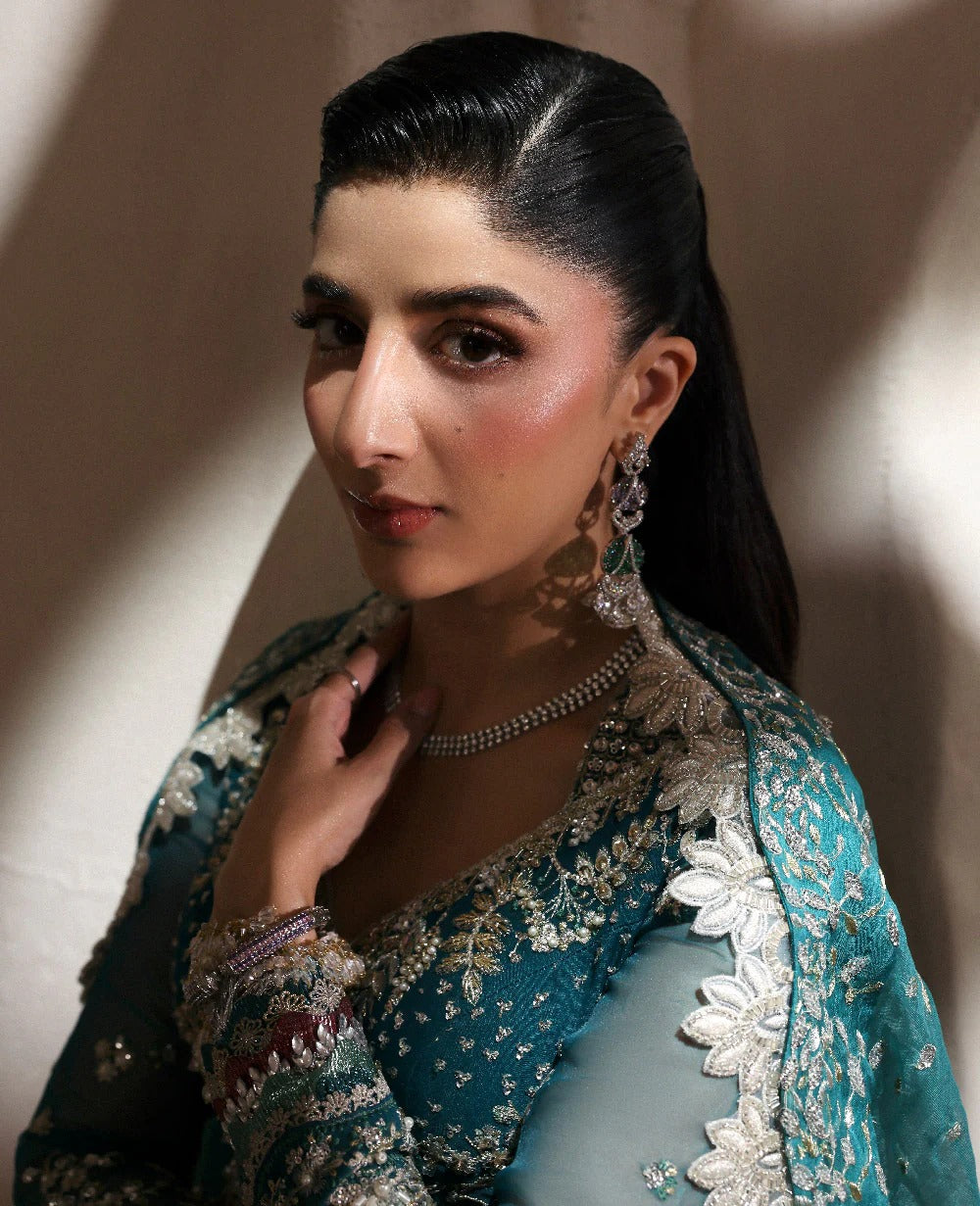 Woman wearing a traditional embroidered outfit with jewelry against a neutral background