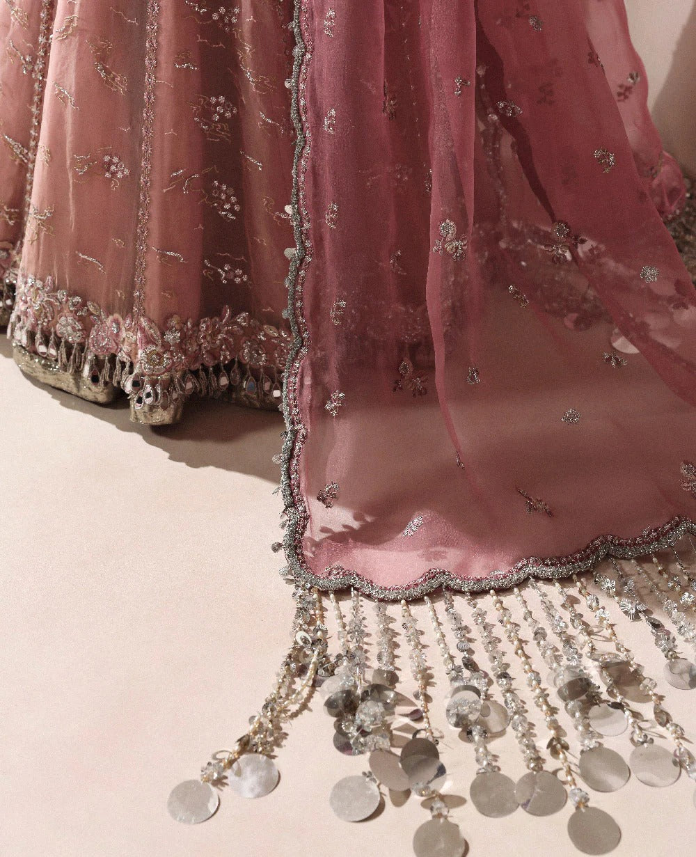 Pink embroidered fabric with tassels on a light background