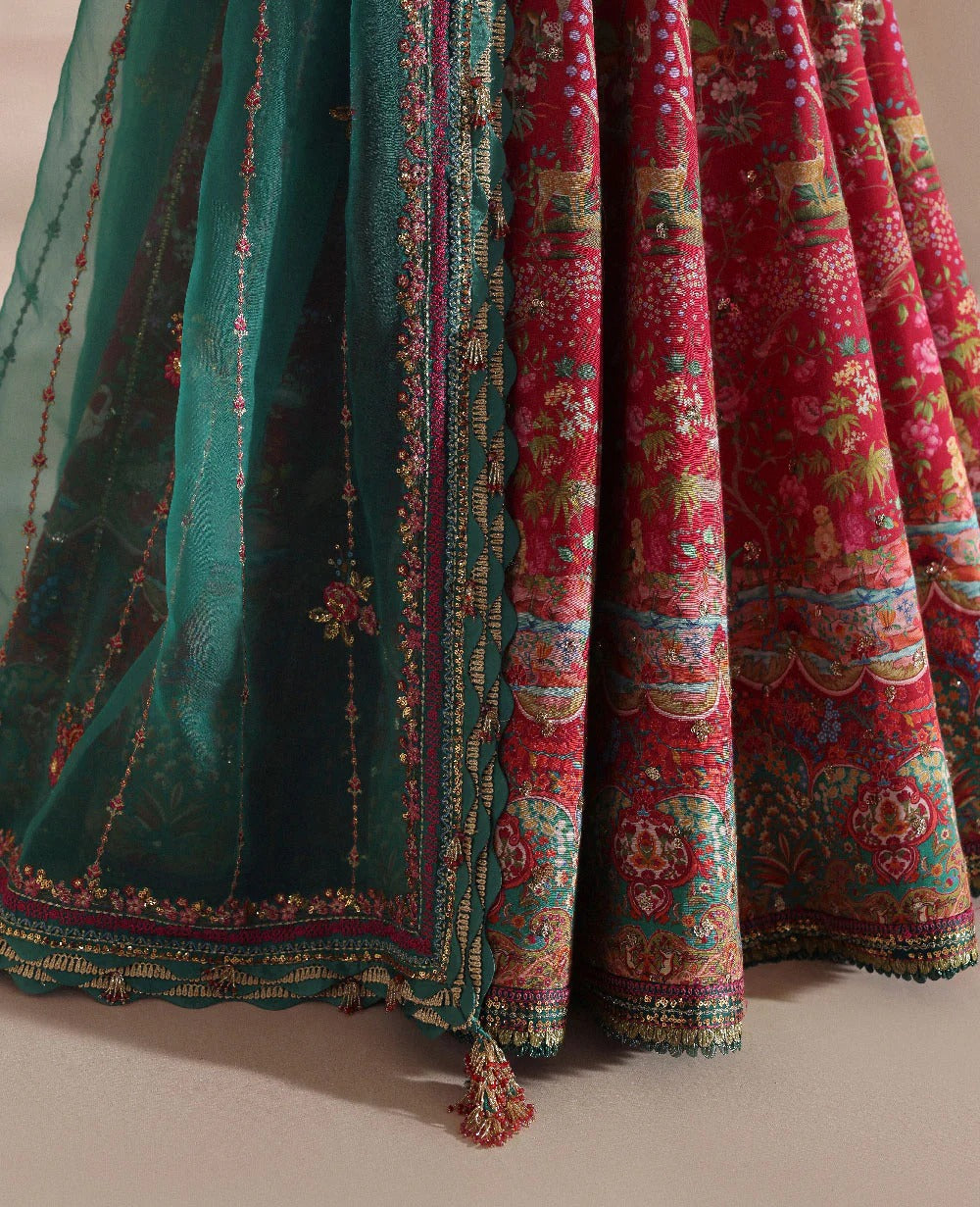 Close-up of a traditional embroidered fabric with green and red patterns on a neutral background