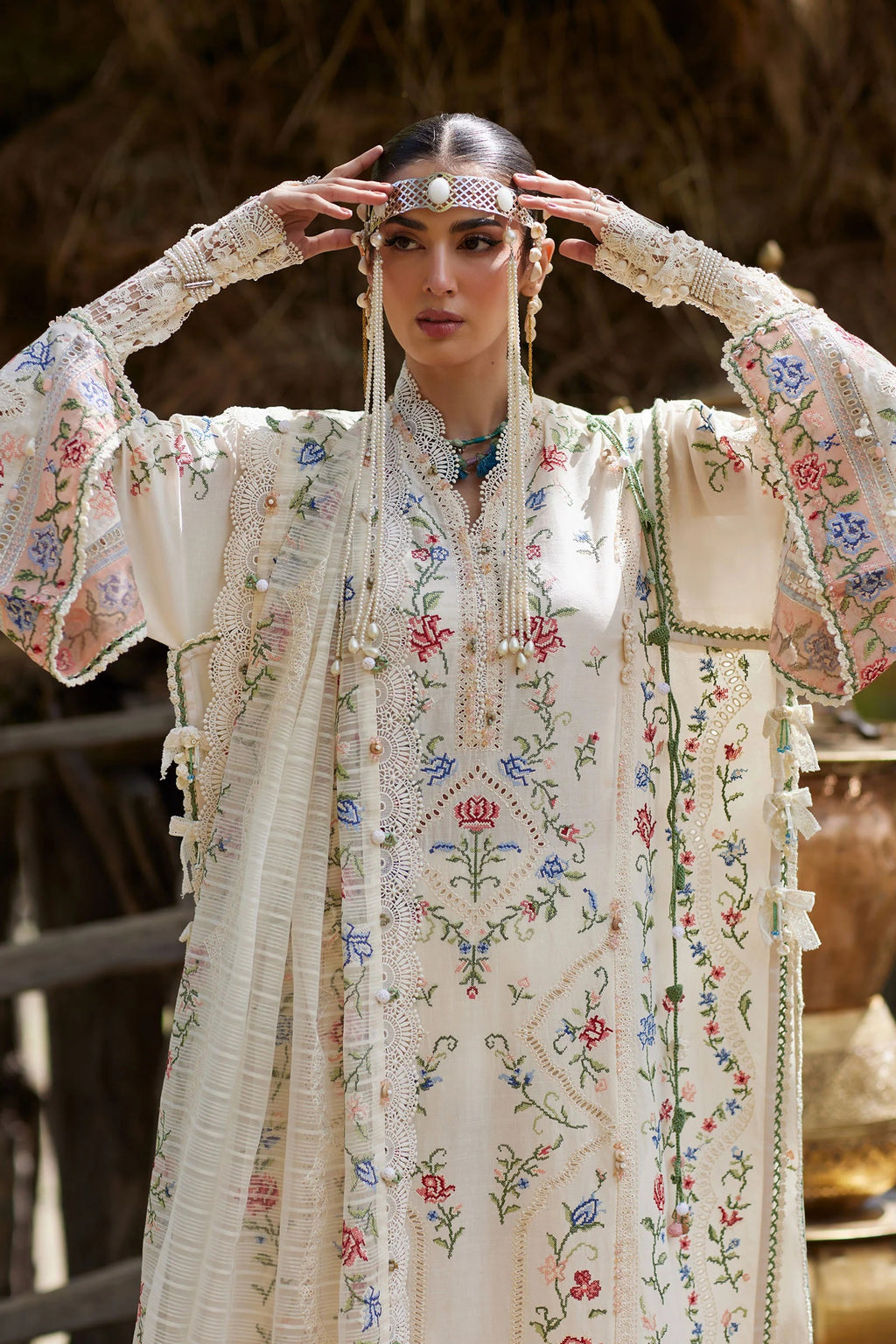 Woman wearing a traditional embroidered outfit with floral patterns.