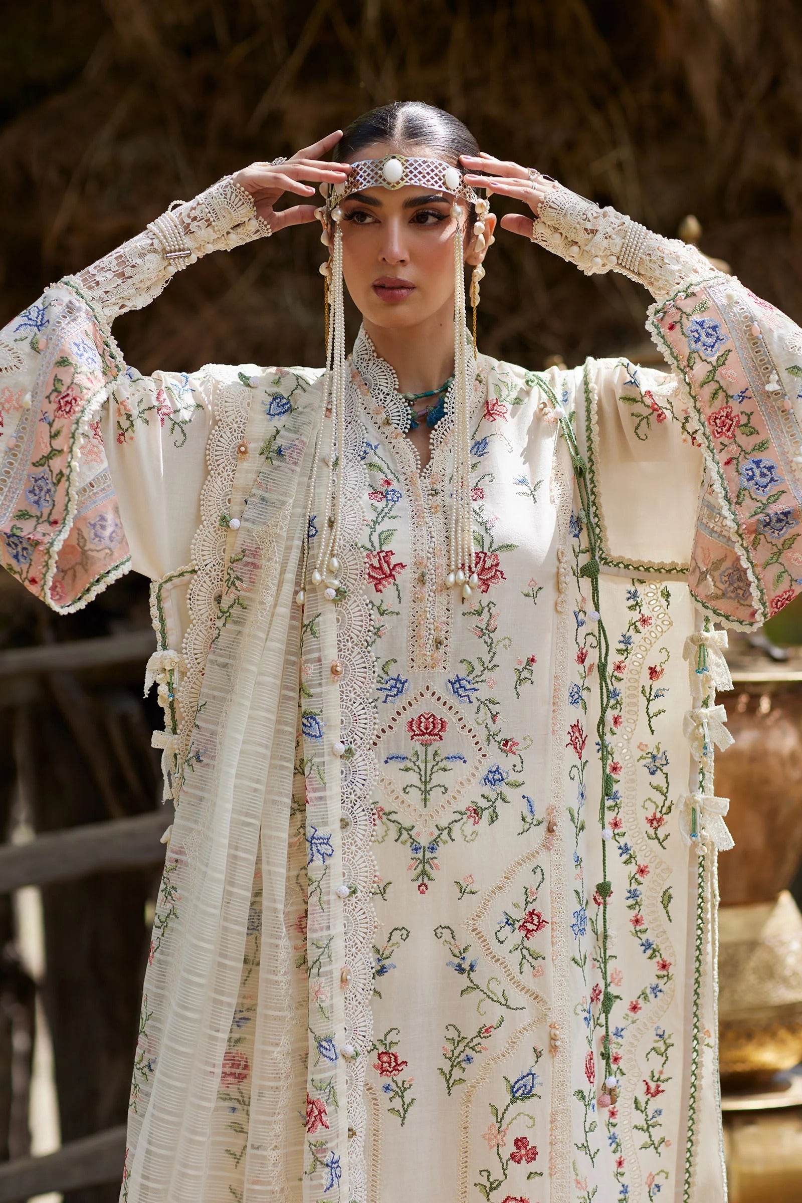 Woman wearing a traditional embroidered outfit with floral patterns.