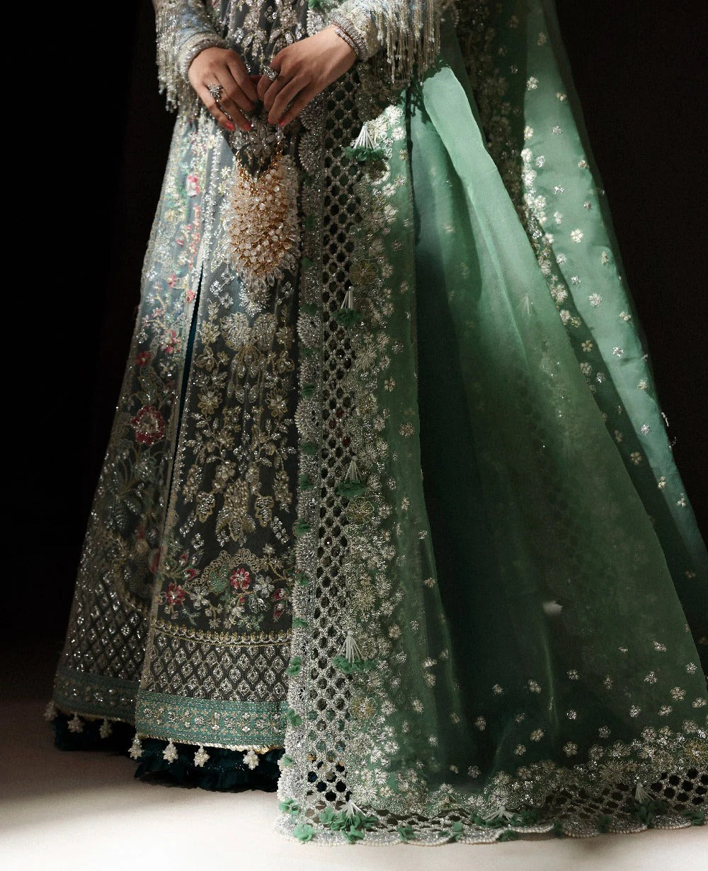 Traditional embroidered outfit with a green dupatta on a dark background