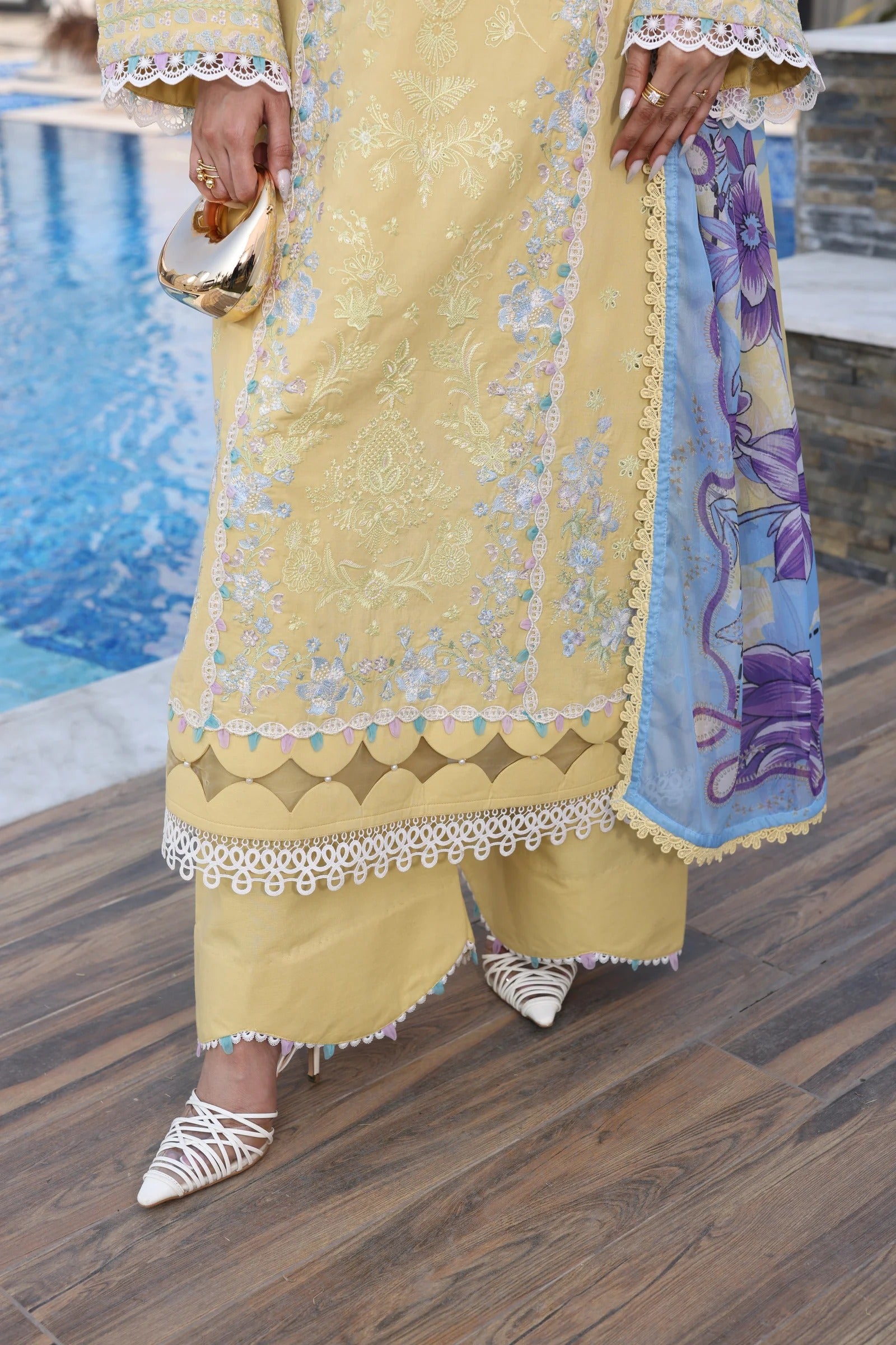 Person wearing a yellow embroidered outfit with a pool in the background