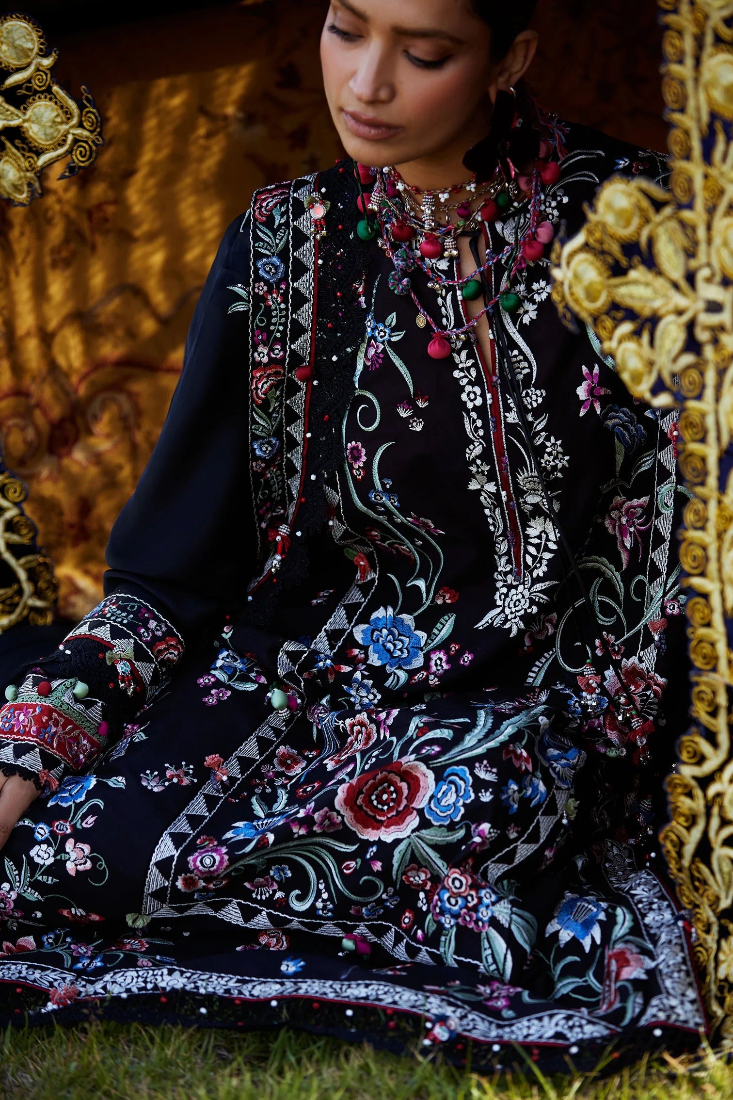 Woman wearing a dark floral dress sitting on a patterned chair.