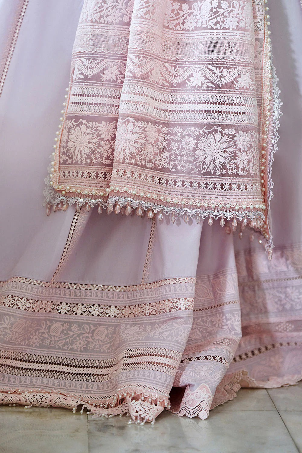 Delicate pink embroidered fabric with intricate patterns on a light background