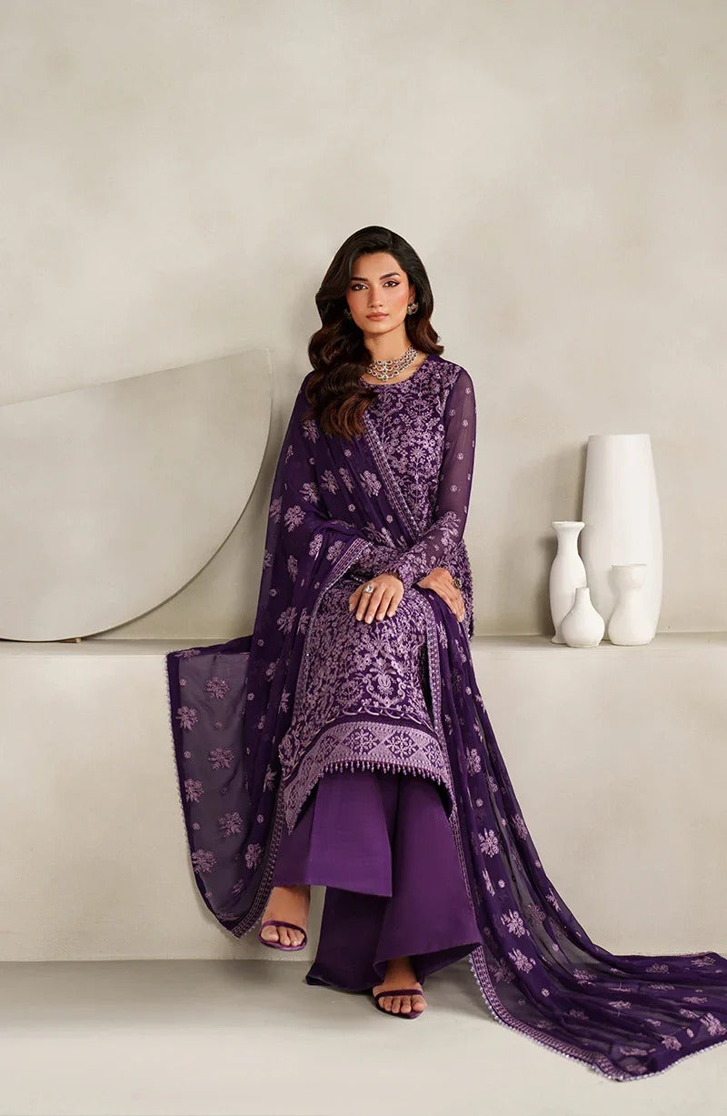 Woman in a purple traditional outfit sitting on a white surface with a neutral background