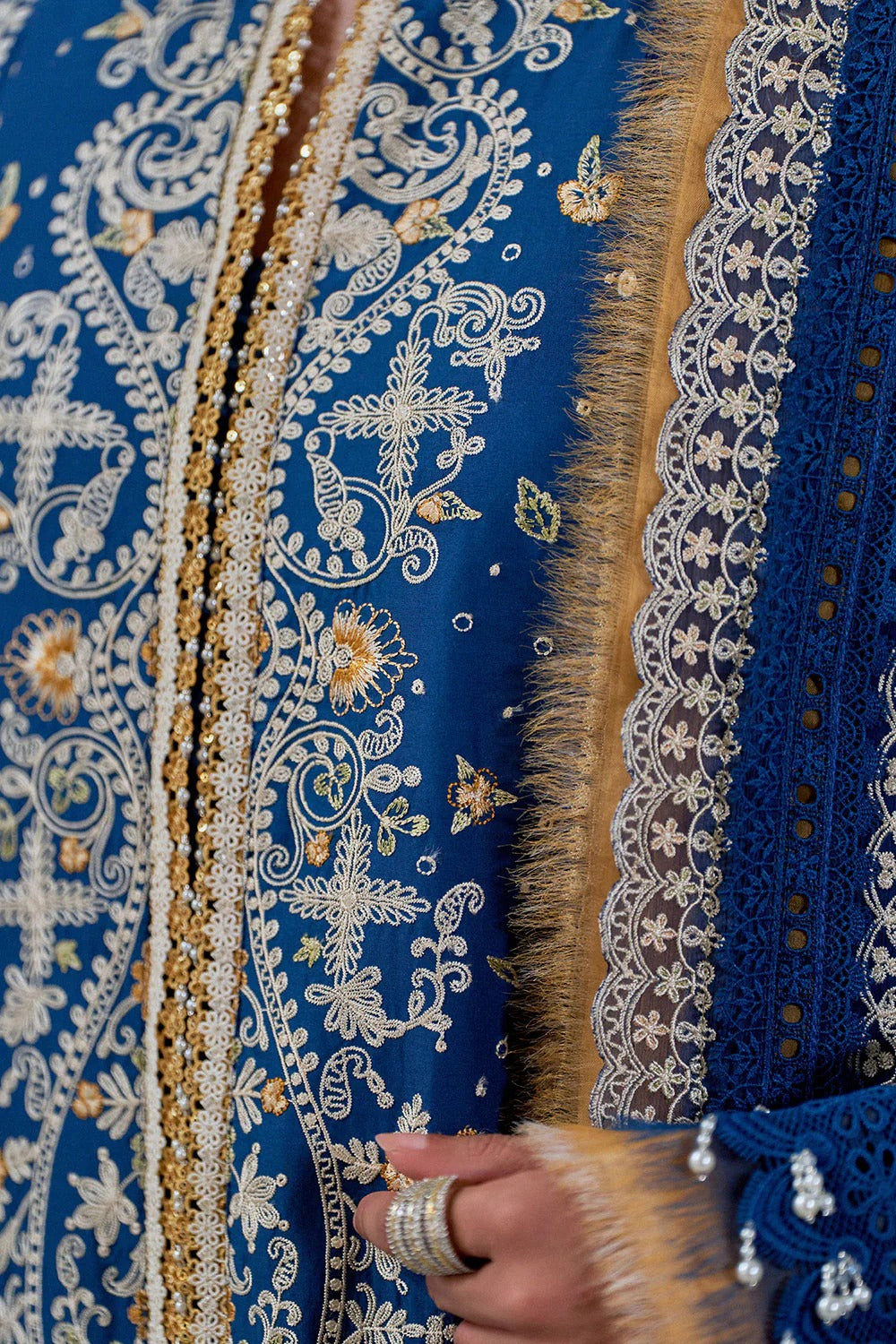 Close-up of a blue fabric with intricate white and gold embroidery