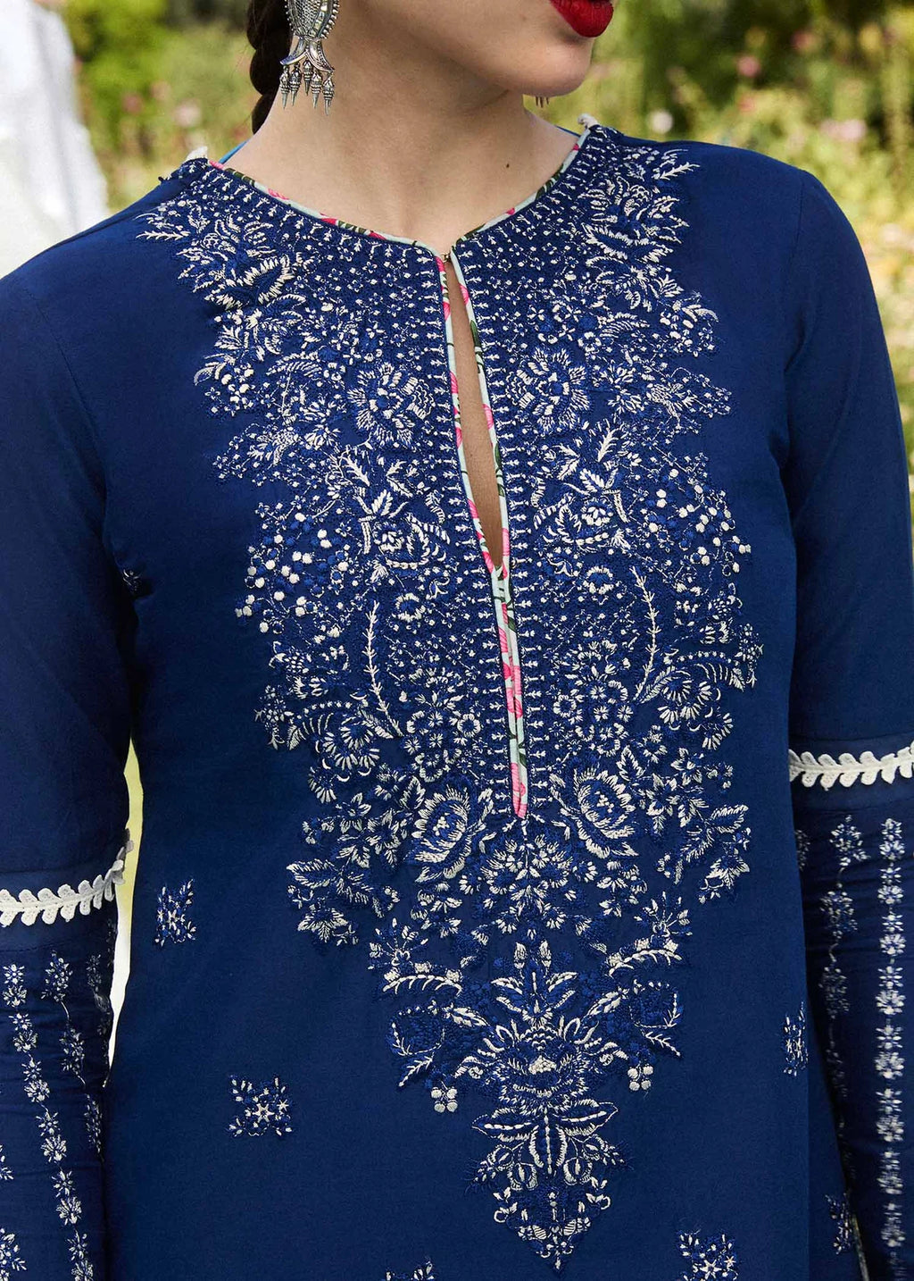 Blue embroidered garment with intricate patterns on a blurred natural background