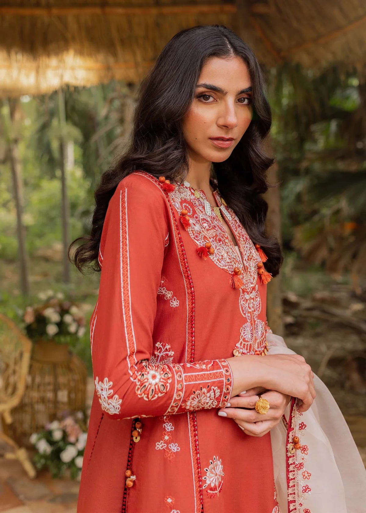 Woman wearing a red embroidered traditional outfit with a blurred natural background