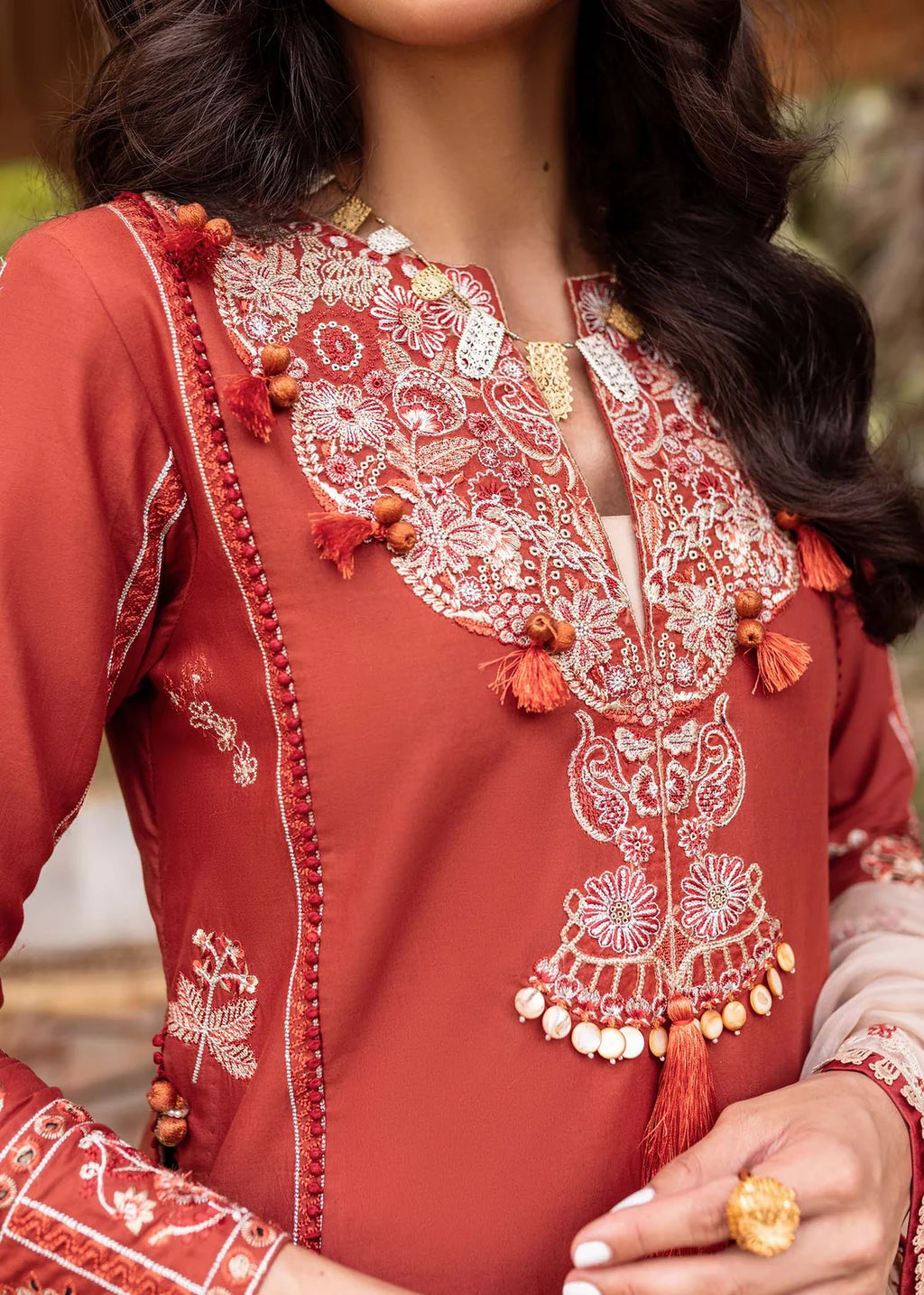 Close-up of a red embroidered garment with intricate patterns and tassels.