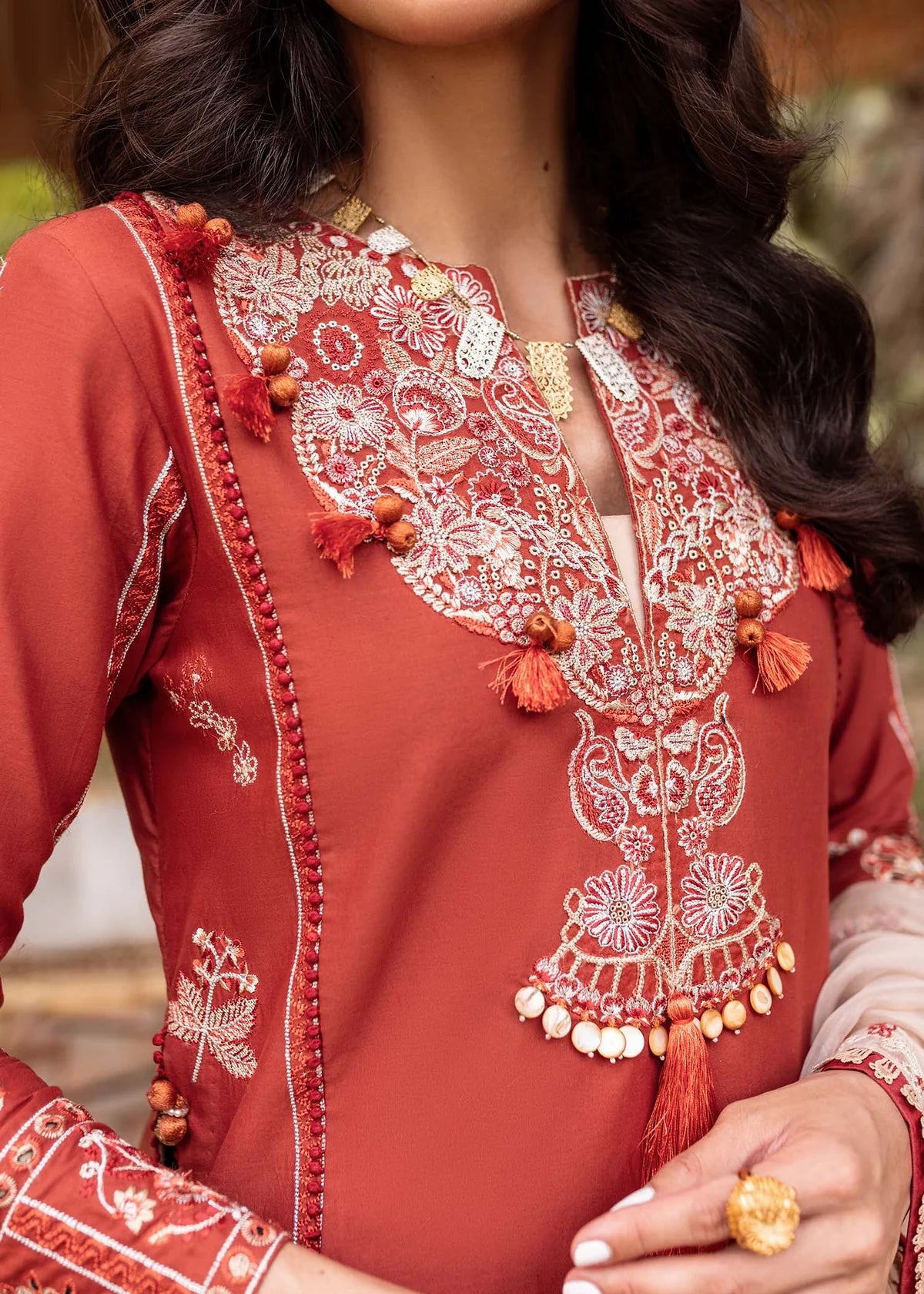 Close-up of a red embroidered garment with intricate patterns and tassels.