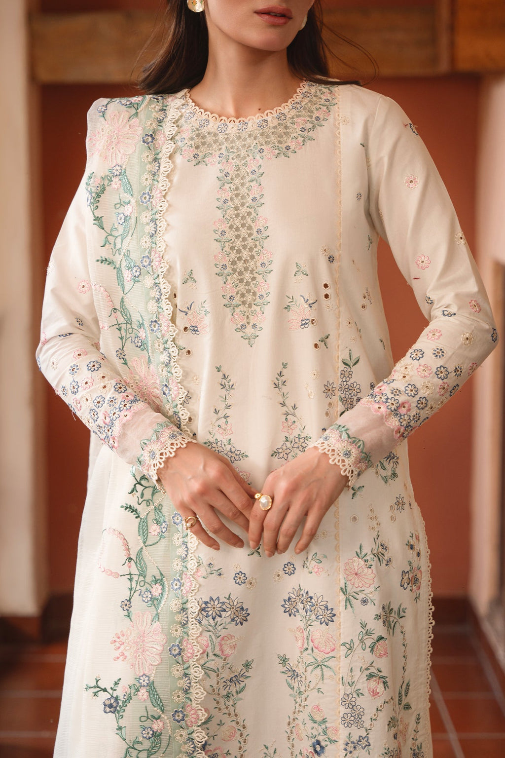Woman wearing a white floral embroidered dress indoors.