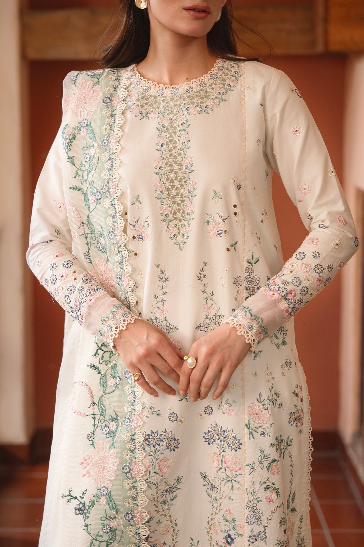 Woman wearing a white floral embroidered dress indoors.