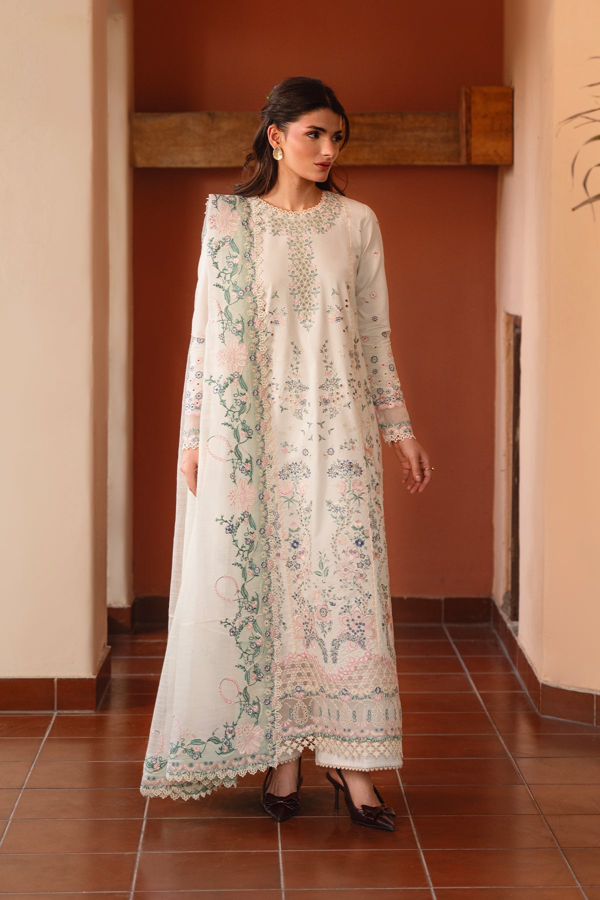 Woman wearing a white floral embroidered dress in an indoor setting