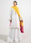 A woman modeling a traditional white three-piece outfit with a bright yellow and magenta dupatta against a plain white studio background.